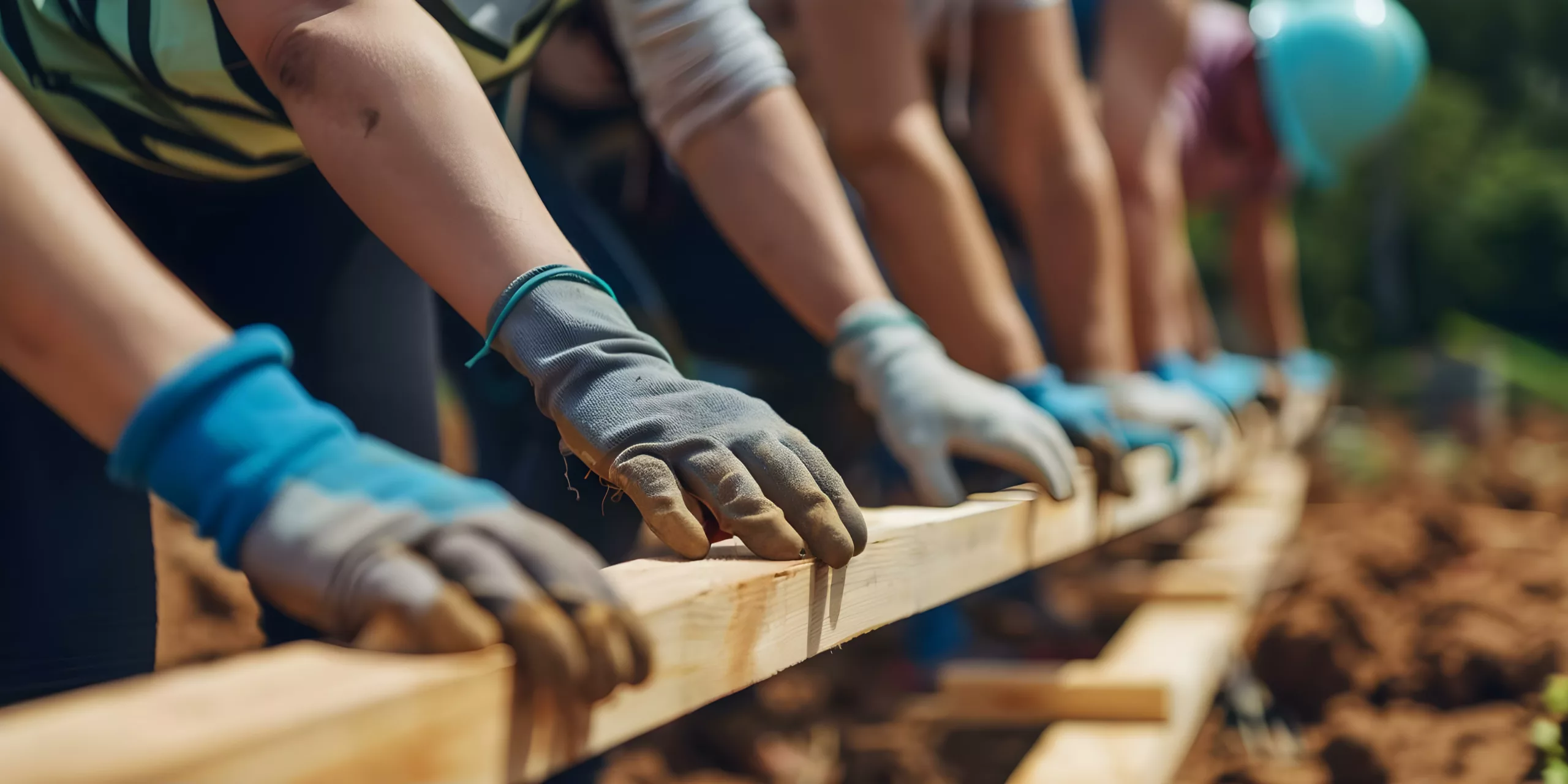 People with work gloves holding wood